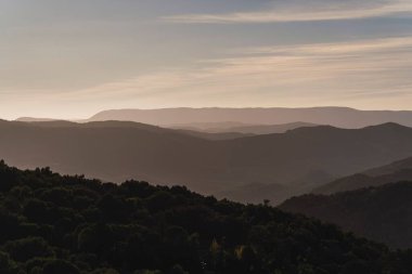 Güneşli bir gökyüzünün altında güzel dağ siluetlerinin havadan görünüşü.