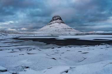 İzlanda 'daki Kirkjufell tepesinde soğuk bir kış günü önünde donmuş bir deniz vardı.