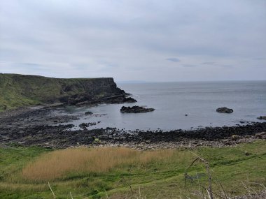 Kasvetli bir günde, Causeway kıyısındaki ineğin körfezi, Bushmills, Kuzey İrlanda