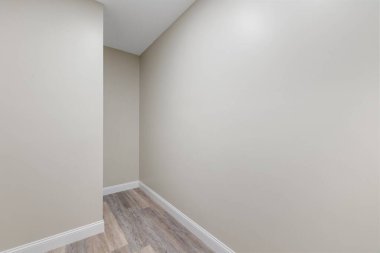 Gri duvarlı ve parke minimalist tarzlı geniş bir odanın içi.