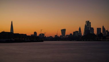 Londra 'nın üzerinde güzel bir günbatımı modern gökdelenlerle altın bir gökyüzüne karşı