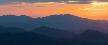 Dağ siluetlerinin üzerinde güzel bir gün batımı manzarası