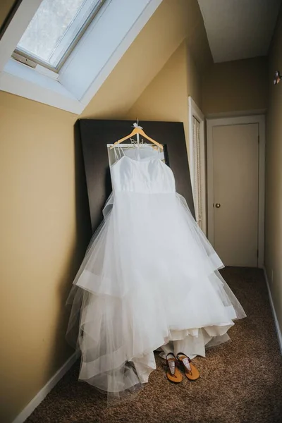 在房间里镜子前挂着的新娘漂亮的白色连衣裙的垂直部分 — 图库照片