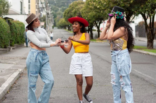 カーニバルの帽子をかぶった3人の若い女性の友人のグループが通りを歩き 楽しんでいます — ストック写真