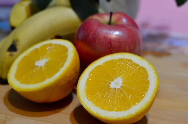 stock image A closeup of a sliced orange and other fruits on a wooden board