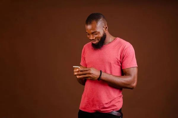 Attractive Happy African Man Scrolling His Phone Isolated Brown Background — Stock Photo, Image