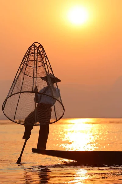 日没時に手作り網で伝統的な方法で魚をキャッチ湖の近くの漁師のシルエット — ストック写真