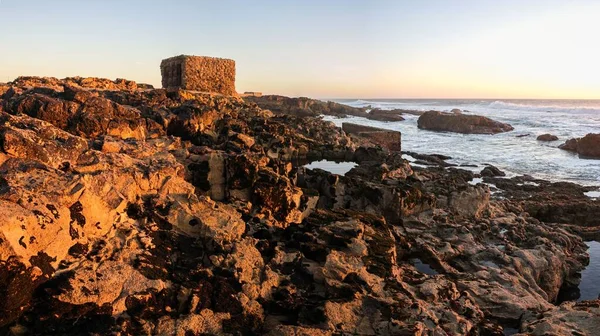 ポルトガルの日没時に太陽の下で波状の海の前の岩の海岸線 — ストック写真