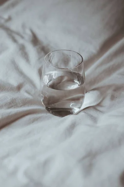 Eine Vertikale Aufnahme Eines Wasserglases Auf Weißem Stoff — Stockfoto