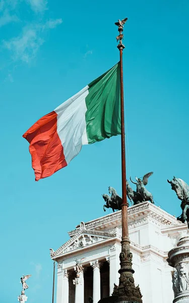 背景にローマのヴィットリアーノ記念碑とイタリアの旗の垂直ショット — ストック写真