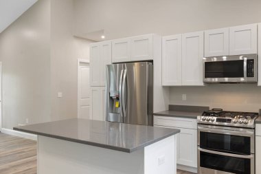 Geniş, modern bir mutfak. İçinde güzel mobilyalar ve aydınlatılmış ışıklar var.