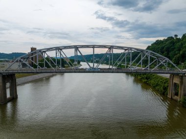 Kirli nehir bulutlu gökyüzü arkaplanı üzerinde güneşli bir Truss köprüsünün alçak açılı yakın çekimi