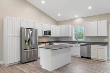 Geniş, modern bir mutfak. İçinde güzel mobilyalar ve aydınlatılmış ışıklar var.