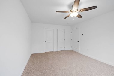 Beyaz duvarları, yanan avizeleri ve ahşap kapıları olan yeni inşa edilmiş bir evin içeriden görünüşü.