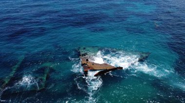 Güneş doğarken küçük dalgalarla dolu bir denizde güzel bir gemi enkazı manzarası.