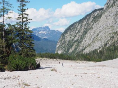 Arka planda gezginlerin ve kayalık yüksek dağların olduğu beyaz bir tarla.