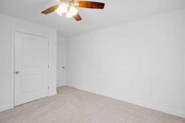 Yeni inşa edilmiş beyaz duvarları, yanan bir avizesi ve ahşap kapıları olan bir evin içeriden görünüşü.