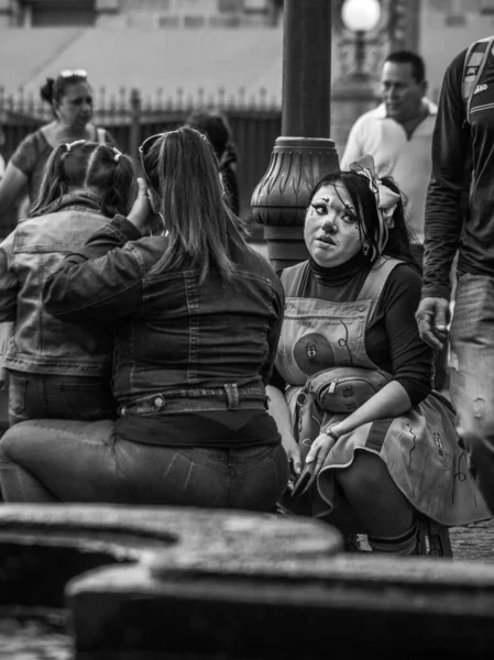 Вертикальный Снимок Женщины Сидящей Улице Нарисованным Мужчиной Множеством Людей Вокруг — стоковое фото