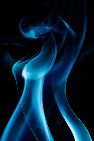 黒い背景に青い煙の垂直ショット — ストック写真