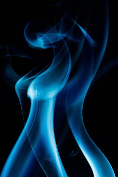 A vertical shot of blue smoke against the black background