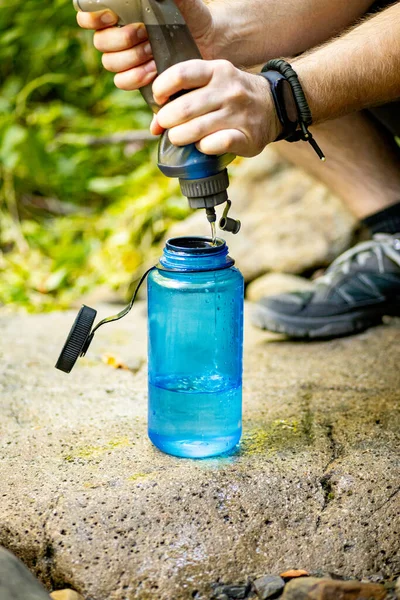 Blisko Dłoni Turysty Wciskających Wodę Niebieskiej Butelki Szerokimi Ustami Skale — Zdjęcie stockowe