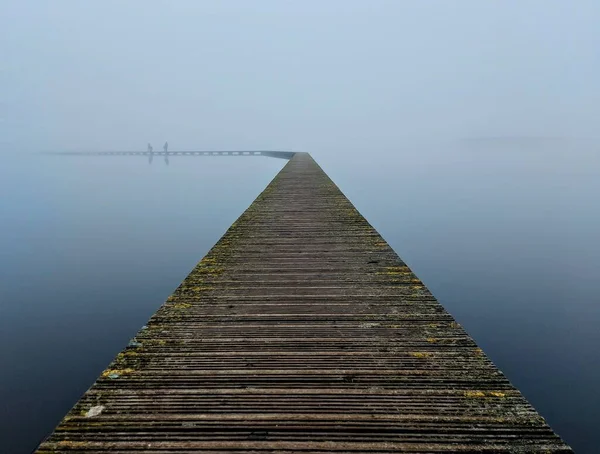霧の日に穏やかな海水の上に木製の桟橋 — ストック写真