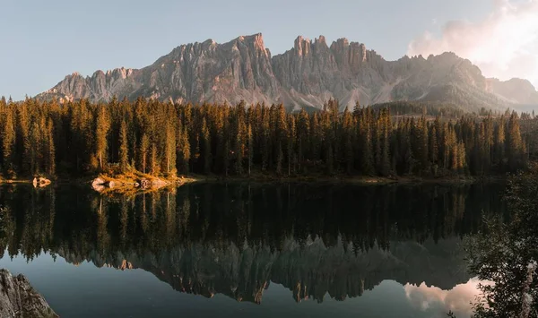 İtalya 'daki ağaçların ve Dolomitlerin yansımasıyla sakin bir göl manzarası.