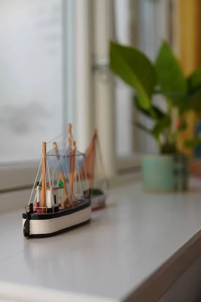 背景がぼやけている植物と窓辺のミニチュアボートのおもちゃの垂直閉鎖 — ストック写真
