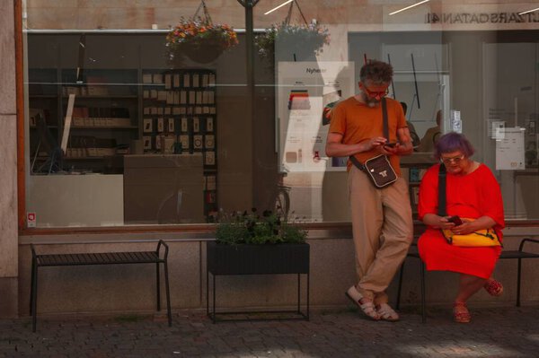Пожилая пара на улице смотрит в свои телефоны