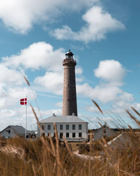 在蓝云的天空下 丹麦国旗在骷髅灯塔前飘扬 垂直射击 — 图库照片