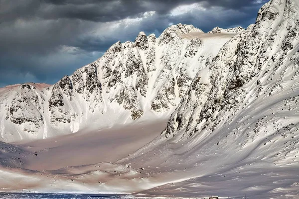 Uma Vista Hipnotizante Montanhas Nevadas Irregulares Sob Nuvens Escuras — Fotografia de Stock