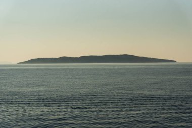 Güneşin doğuşuyla deniz manzarası sisli dağlar ve berrak gökyüzü arkaplanı