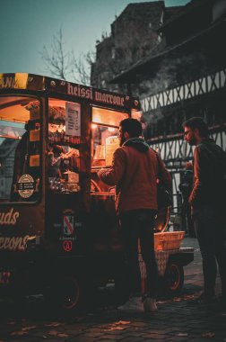 Fransa 'nın Strazburg kentindeki Noel pazarından kestane alan iki adamın dikey çekimi.