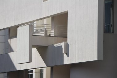 Güneşli bir günde eşsiz balkonları olan modern bir bina cephesi.