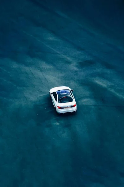 一辆白色宝马汽车在外面一条深蓝色的路上行驶时的垂直高角镜头 — 图库照片