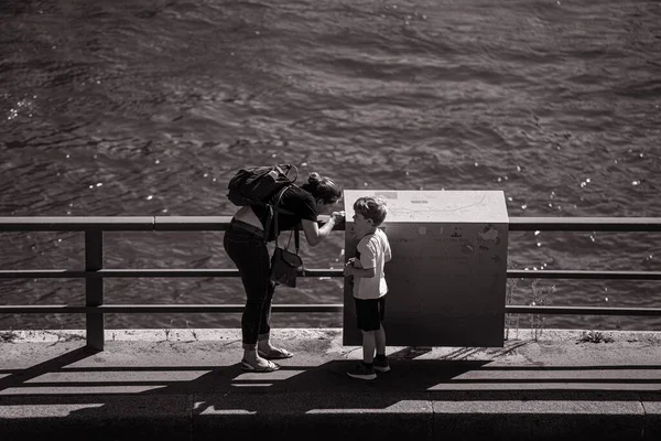 晴れた日フランスリヨンの橋の上に立っている彼女の子供と話す母親のグレースケール — ストック写真
