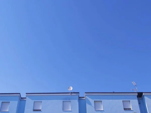 stock image The top of the blue modern building with windows under the blue sky