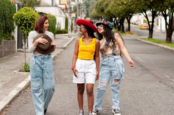 カーニバルの帽子をかぶった3人の若い女性の友人のグループが通りを歩き 楽しんでいます — ストック写真