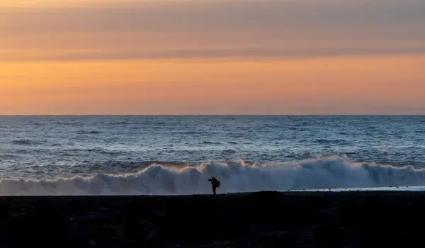 レイニサフィヤラを背景に大きな泡の波と夕日の空を持つ写真家のシルエット — ストック写真