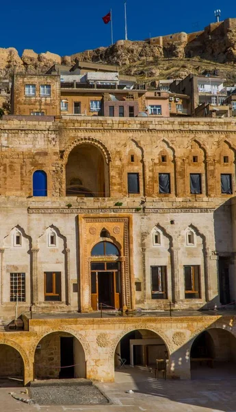 Türkiye 'nin Mardin kentindeki geleneksel taş evin dış cephesi, güneşli bir günde, tepesinde Türk bayrağı olan