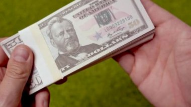 Ulysses S. Grant 'in portresi olan elli dolarlık banknotları tutan ellerin yakın çekimi..