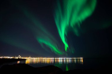 Reykjavik, İzlanda üzerindeki parlak yeşil kuzey ışıklarının alçak açılı görüntüsü.