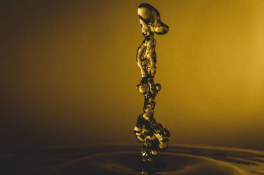 Sarı arka ışıklandırmalı ve yarı-karanlık arka planda bir su damlasının yakın çekimi