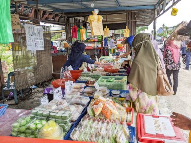 Banjar topluluğunun çeşitli geleneksel yemeklerini seçen bir kadın.