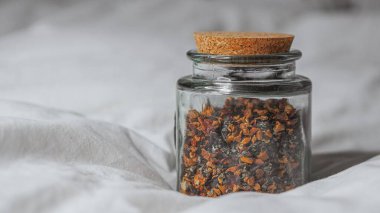 Yumuşak beyaz yatakta bir kavanoz siyah çay.