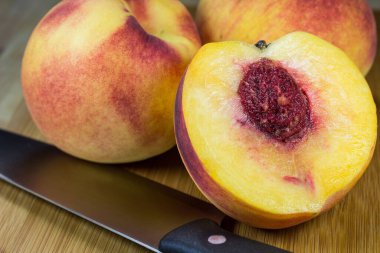 Bambu kesme tahtasına yerleştirilmiş üç sulu şeftalinin yakın plan çekimi.