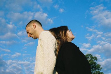 Arka planda güneşli, bulutlu arka planda sırt üstü duran bir çiftin yakın çekimi.