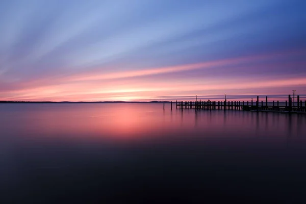 朝の日の出の間に広大な海に反射して魅惑的な赤い輝く空の長い露出 — ストック写真