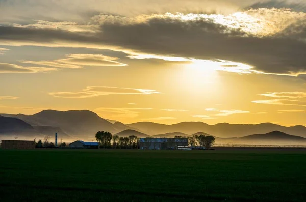 Malowniczy Widok Farmy Zielonym Polu Pod Zachmurzonym Niebem Zachodzie Słońca — Zdjęcie stockowe