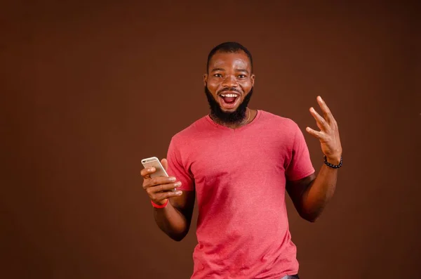 Przystojny Podekscytowany Afroamerykanin Telefonem Brązowym Tle — Zdjęcie stockowe